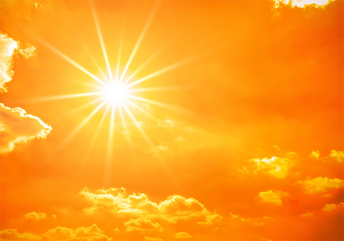 Bright sun in an orange-yellow sky with small clouds.