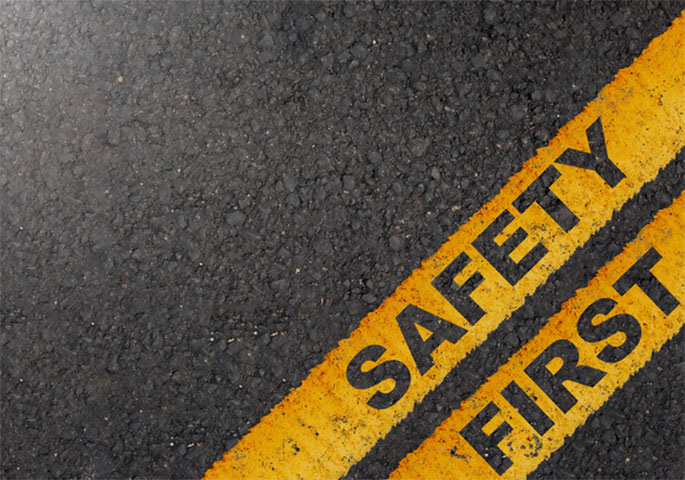 Dark asphalt road with warning sign "SAFETY FIRST"