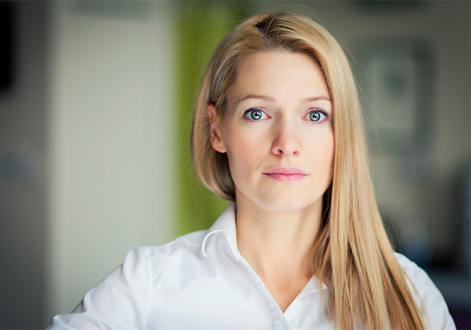 Blonde woman in white shirt stares straight ahead.