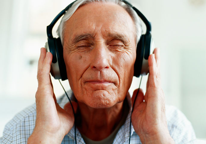 älterer Mann mit modernen Kopfhörern in Musik vertieft