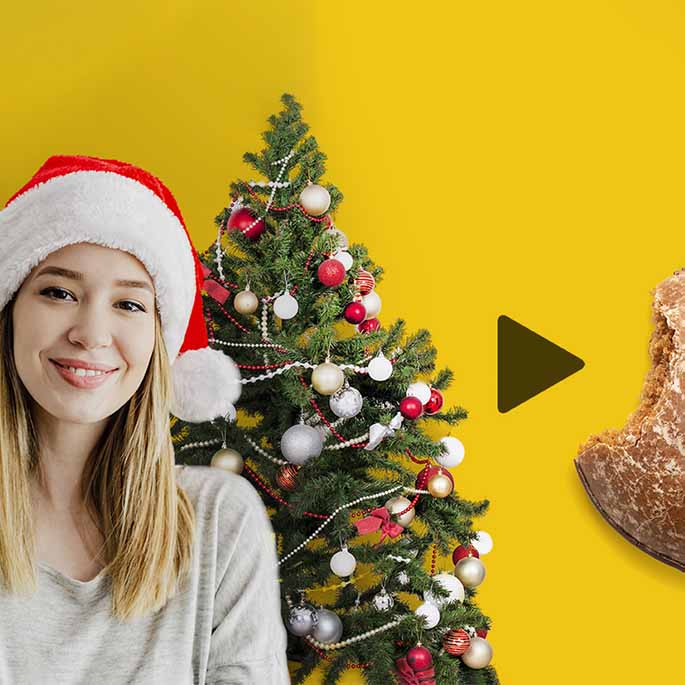 Pointer pointing from woman with Santa hat in front of Christmas tree to bitten gingerbread.