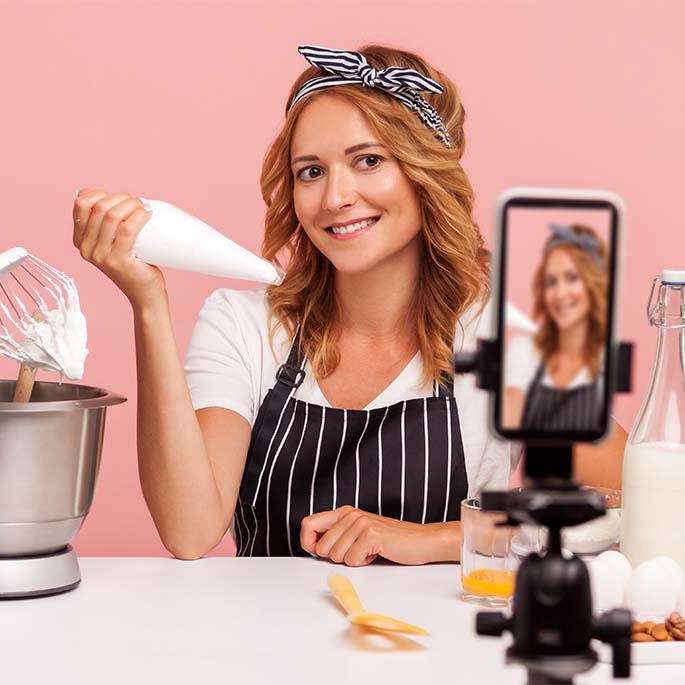 Food blogger baking in front of cell phone on tripod.