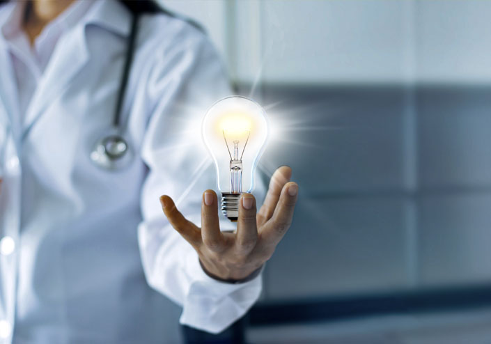 Doctor holds glowing lightbulb in his hand.