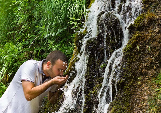 Man drinks from waterfall