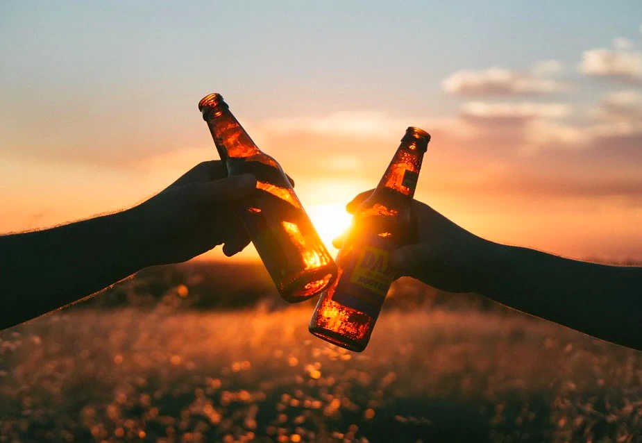 Beerflaschen anstossen bei Sonnenuntergang